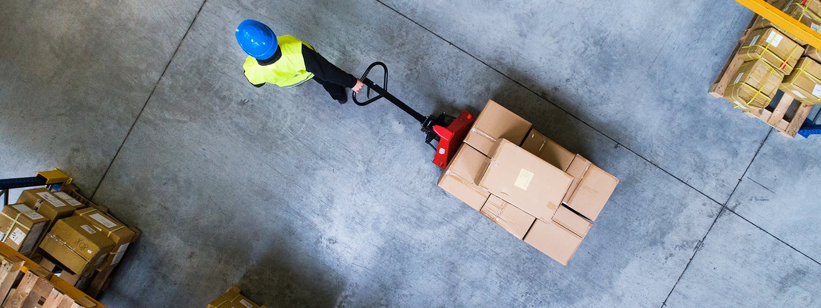 Male warehouse worker pulling a pallet truck.