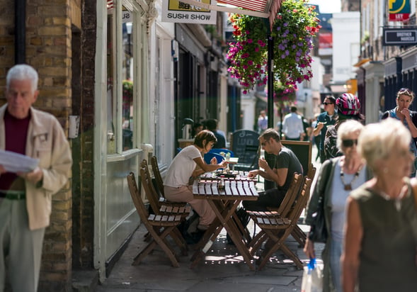 Shoppers and people eating outside restaurants in Camden Passage, Islington
